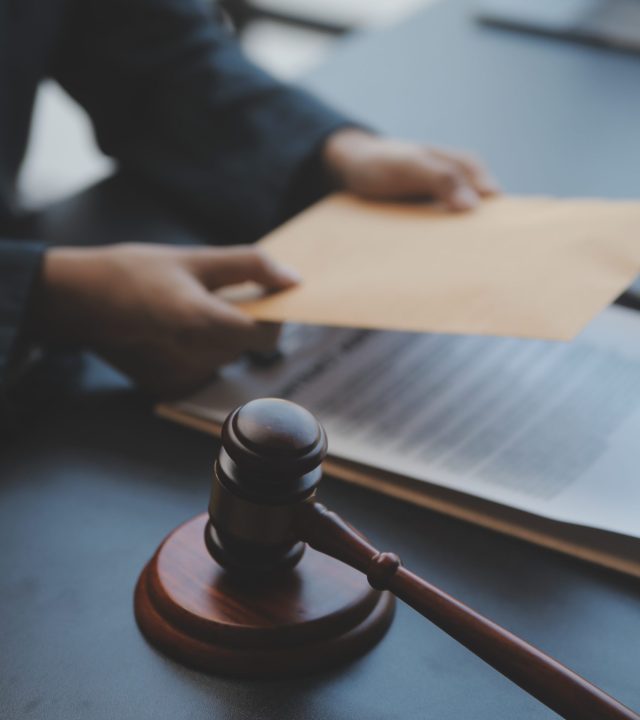 Business and lawyers discussing contract papers with brass scale on desk in office. Law, legal services, advice, justice and law concept picture with film grain effect